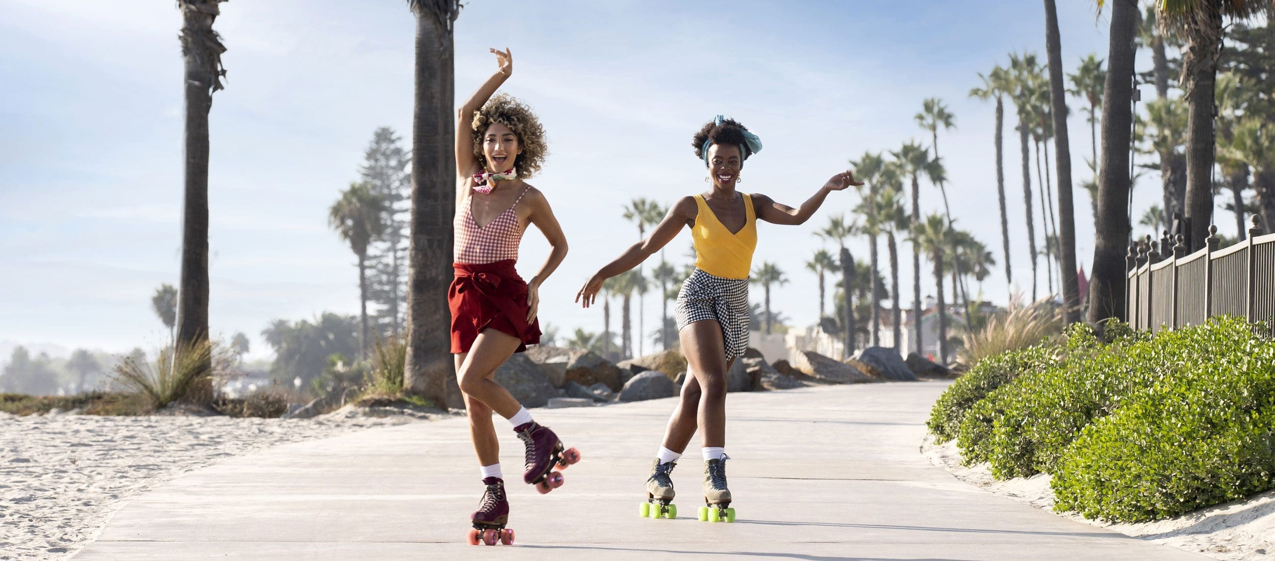 Two women roller skating by the beach