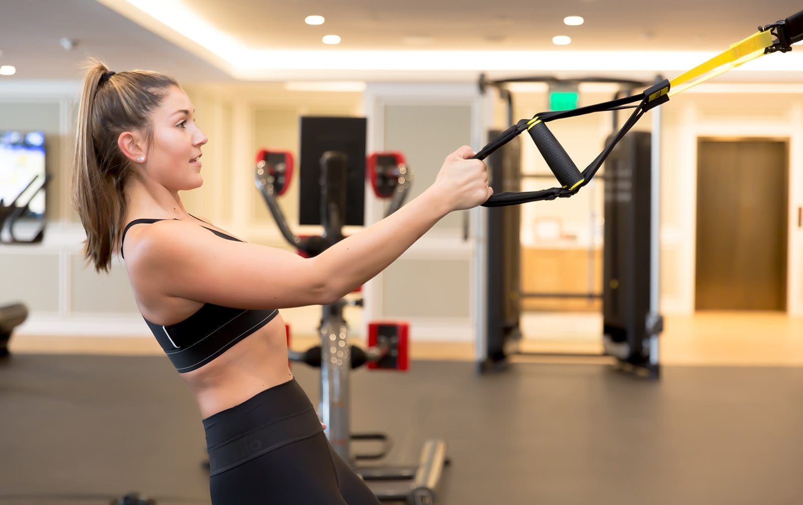 Woman in fitness clothes doing a workout with suspension bands