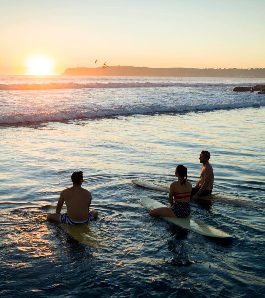 Three friends surfing at sunset